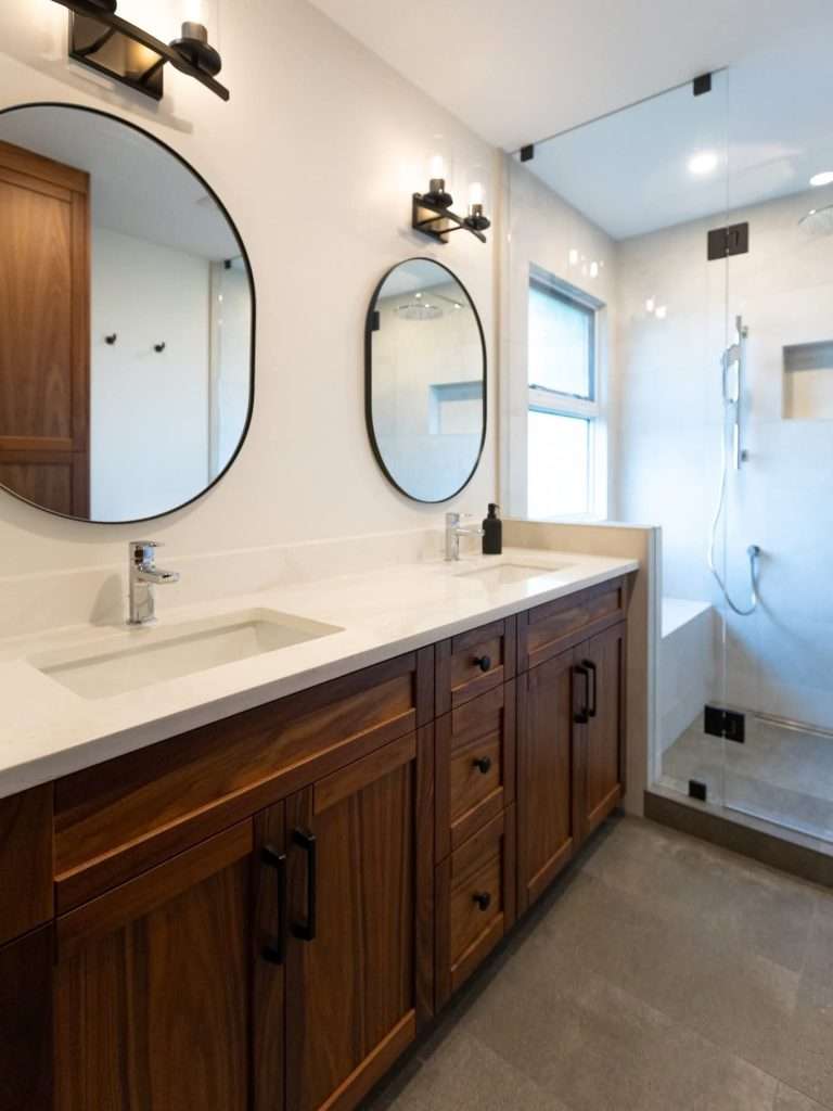 Finished double vanity with Vicostone Marmoris quartz, two round mirrors and wood cabinetry in Surrey.